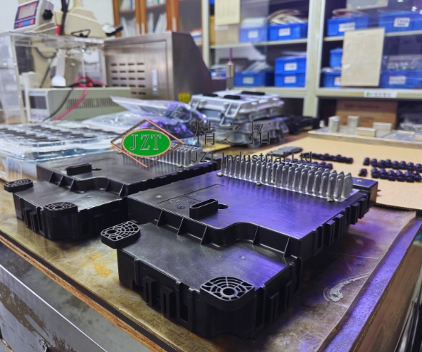 Black molded plastic components arranged on a workbench