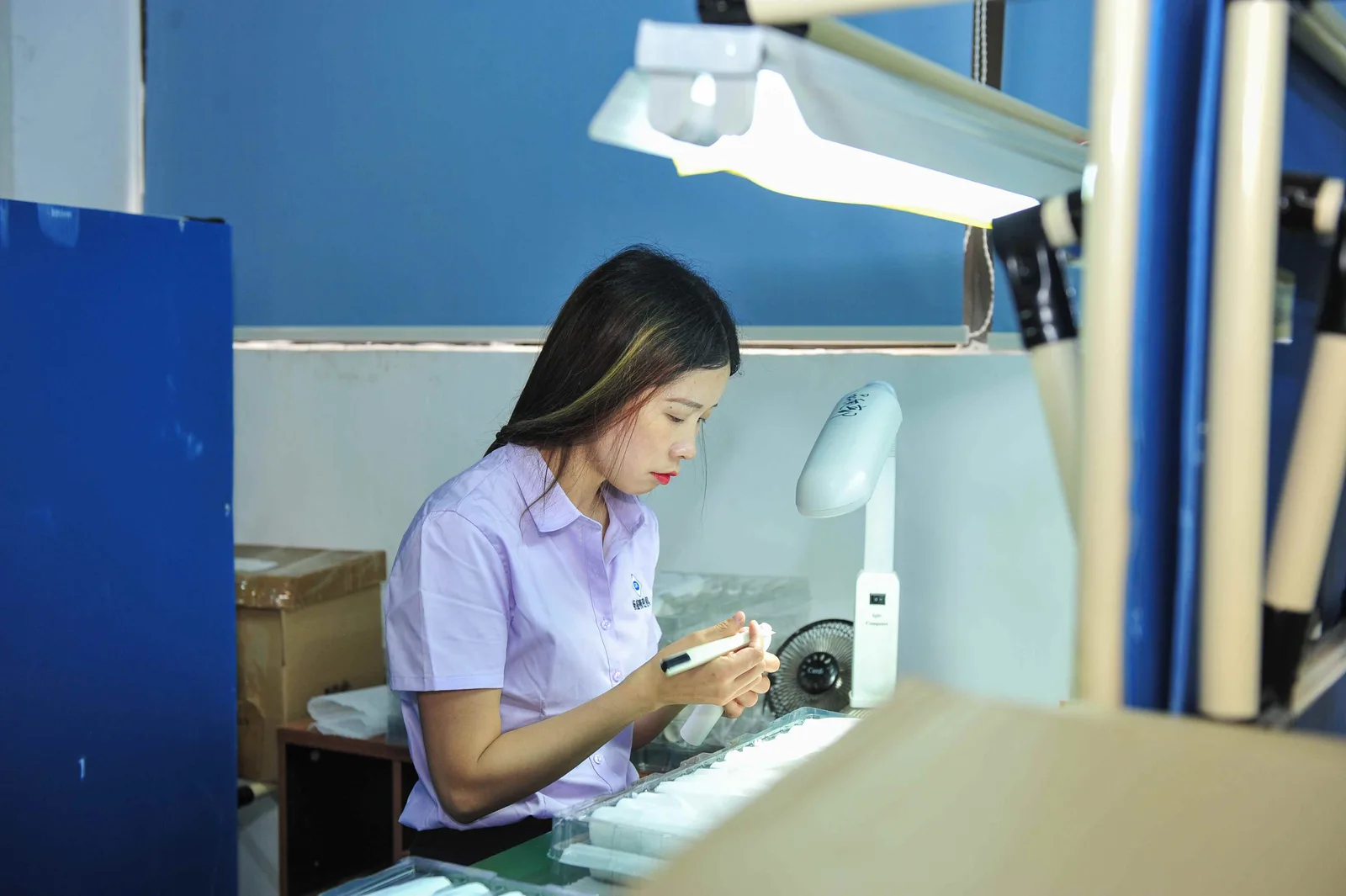 Worker inspecting a plastic component under a magnifier